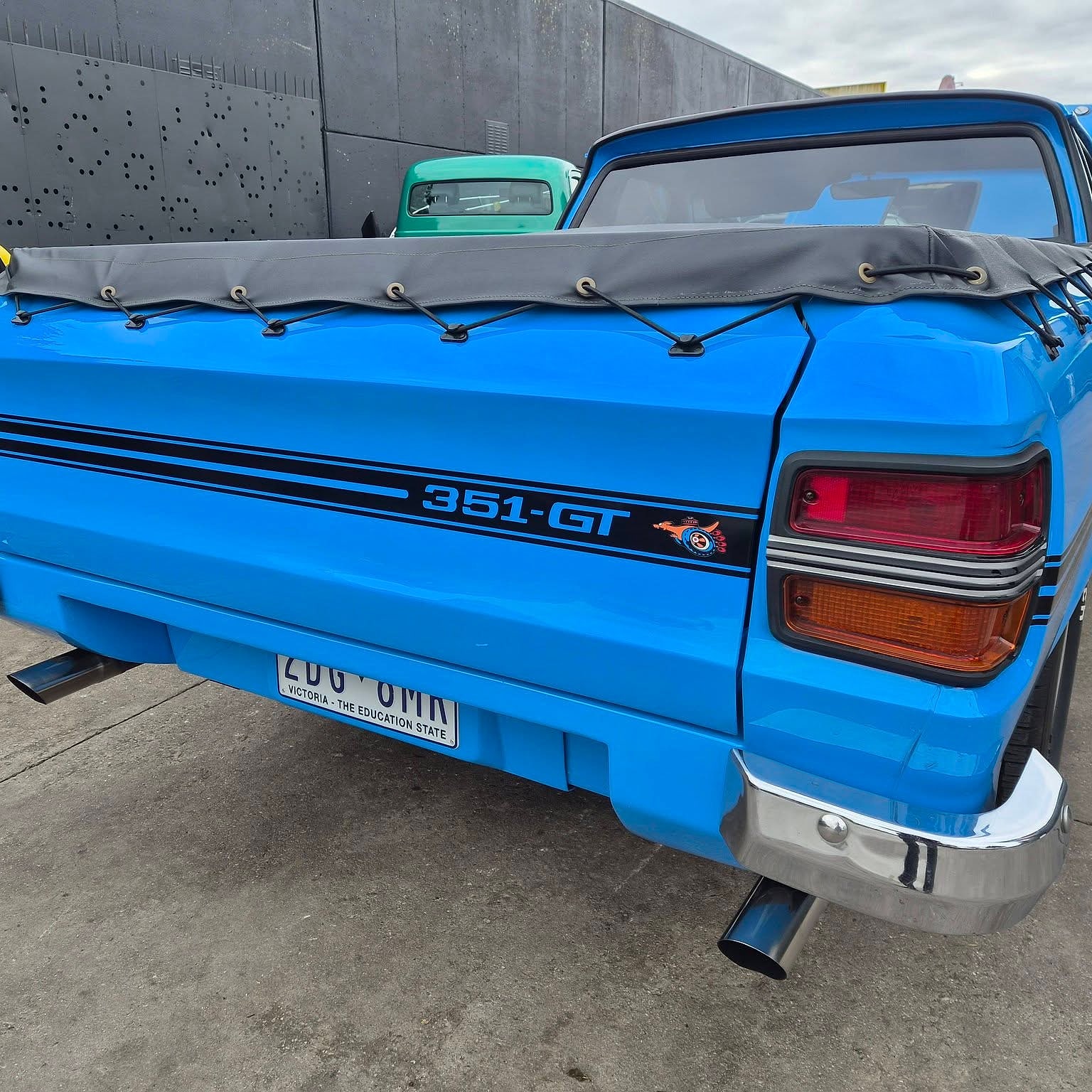 The rear of a blue Falcon GT ute with 351-GT lettering on the tailgate and a laced down tonneau over the tray