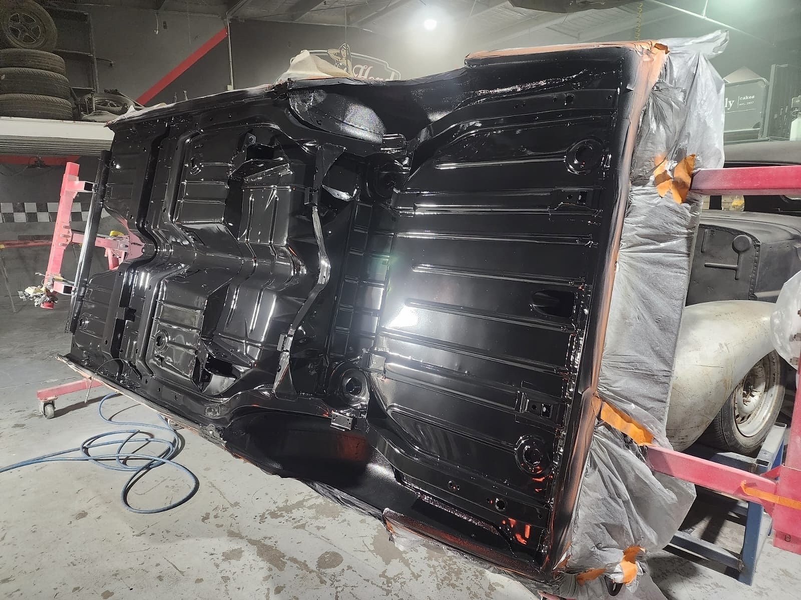 The same car body shell on the rotisserie, the underside now painted in gloss black