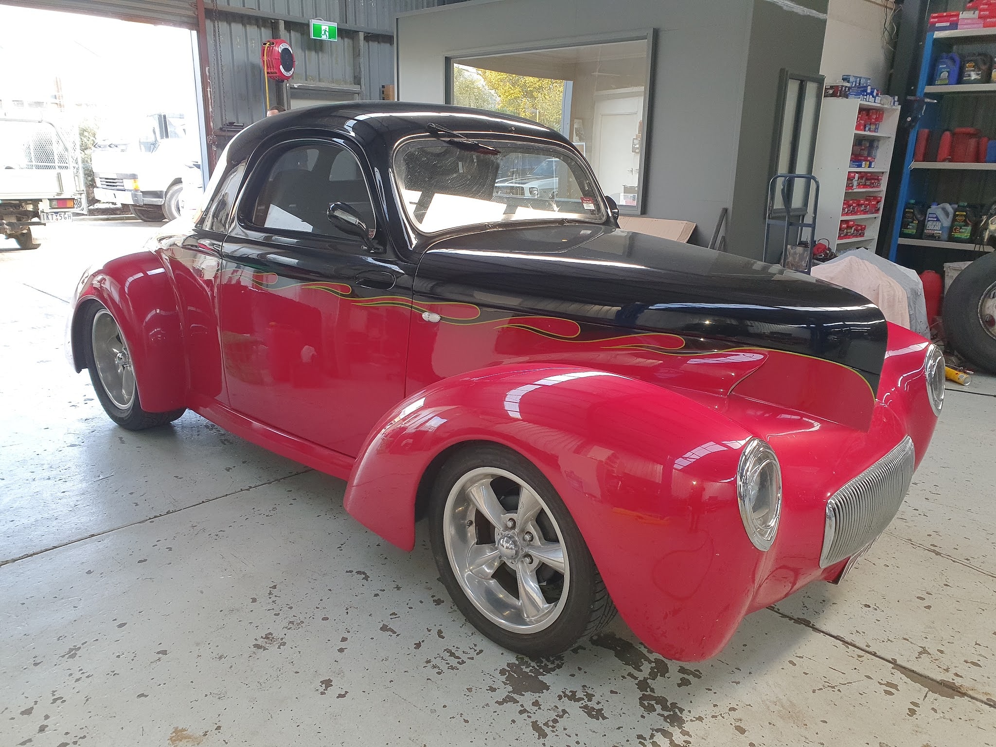 A Willys coupe finished in red with a black bonnet and roof and yellow edged flames down the side